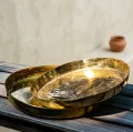 Handcrafted decorative brass plates with intricate engraved designs displayed as elegant wall decor