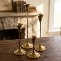 A premium set of four staggered-height vintage brass taper candle holders by OneTrend.