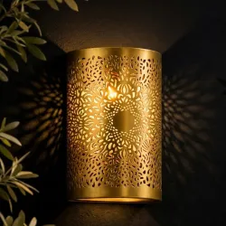 Handmade solid brass wall lamp with intricate floral cutwork design creating decorative ambient lighting and elegant shadow patterns for luxury interior décor.