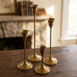 A premium set of four staggered-height vintage brass taper candle holders by OneTrend.